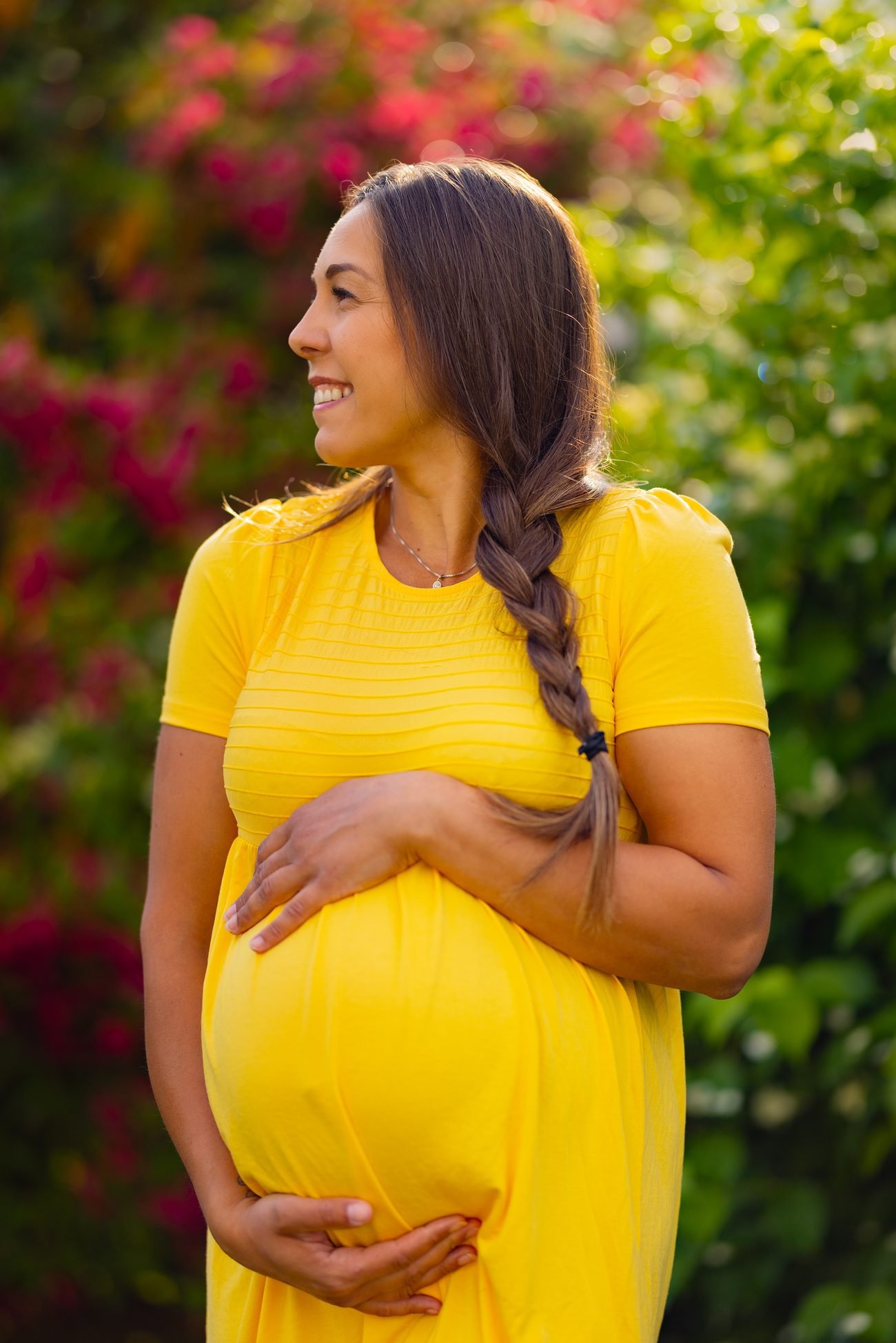 Pregnant woman in a garden wearing a yellow dress