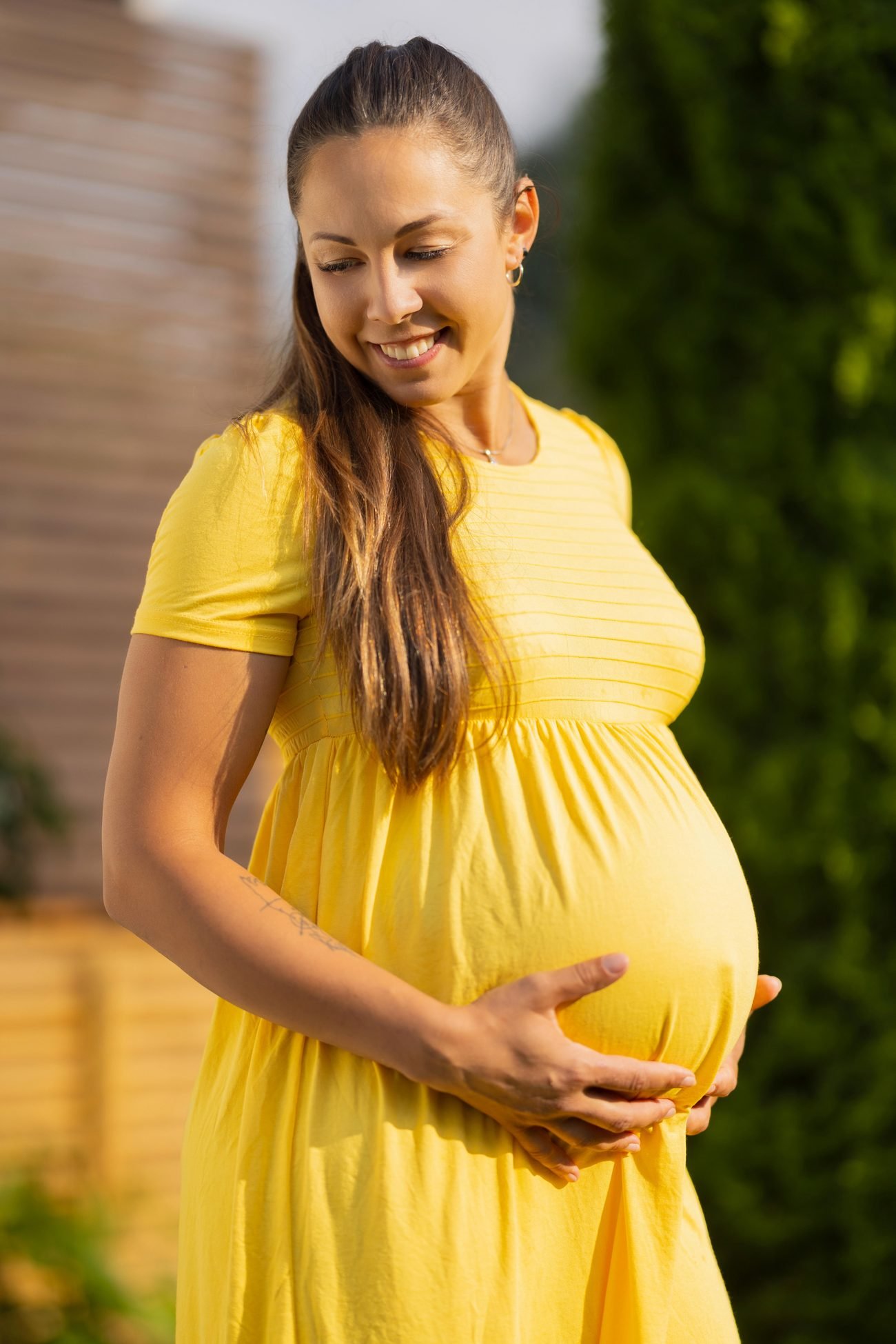 Pregnant woman smiling in a yellow dress